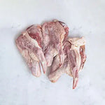 Raw duck offcuts with skin and bone on white marble surface