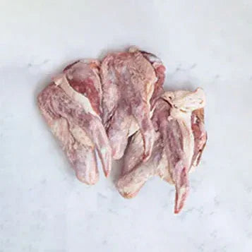 Raw duck offcuts with skin and bone on white marble surface