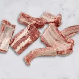 Raw pork offcuts with bones on a white marble surface