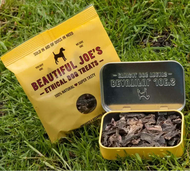 Yellow bag and tin of Beautiful Joe's ethical dog treats on green grass